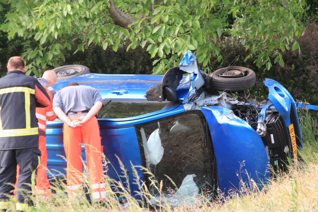 Auto belandt op zijn kant in weiland
