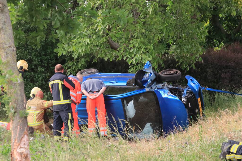 Auto belandt op zijn kant in weiland