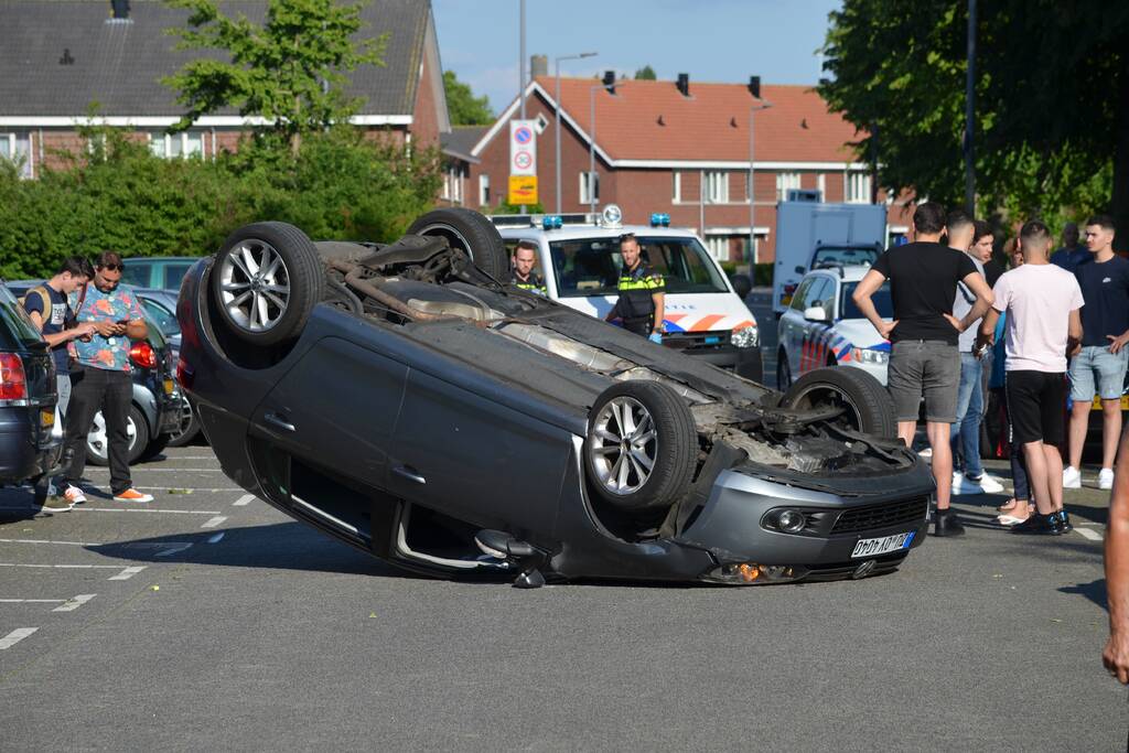 Auto op zijn kop na aanrijding met geparkeerde auto