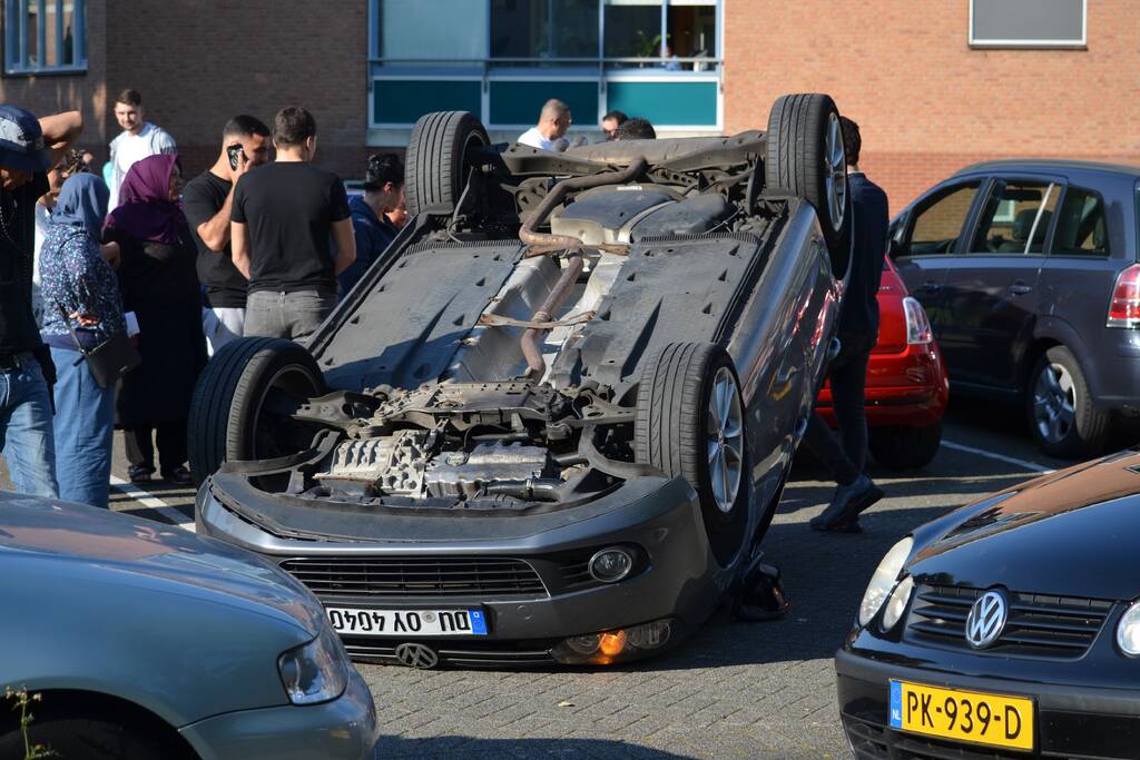 Auto op zijn kop na aanrijding met geparkeerde auto