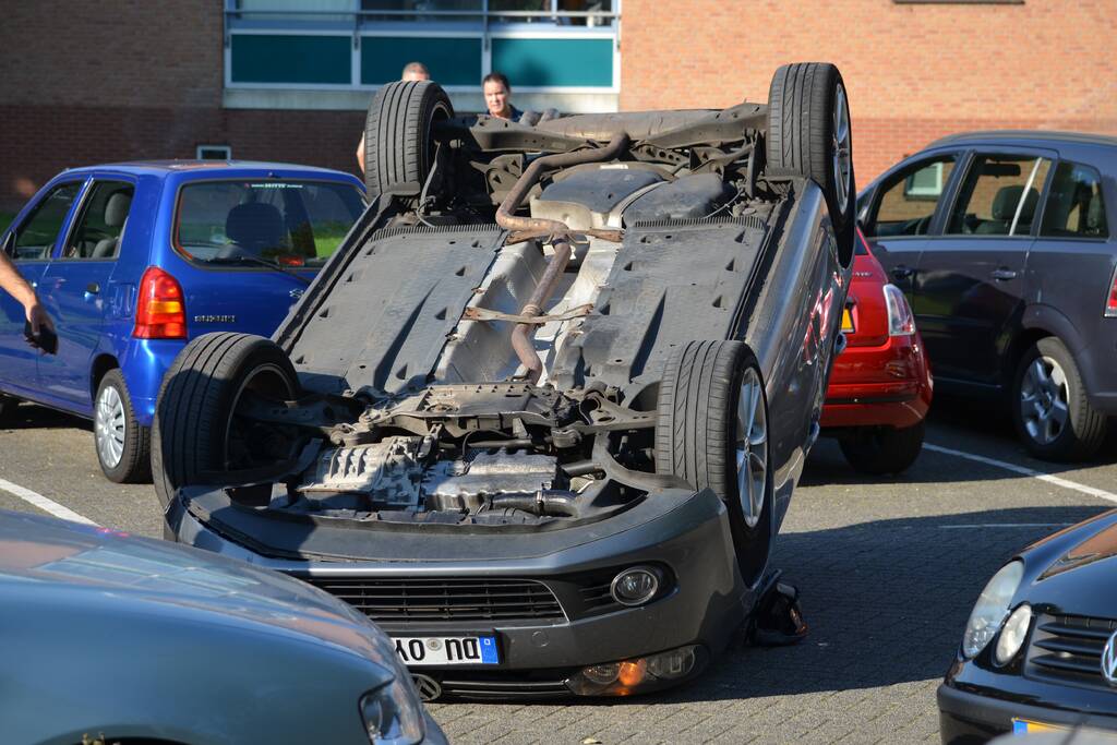 Auto op zijn kop na aanrijding met geparkeerde auto