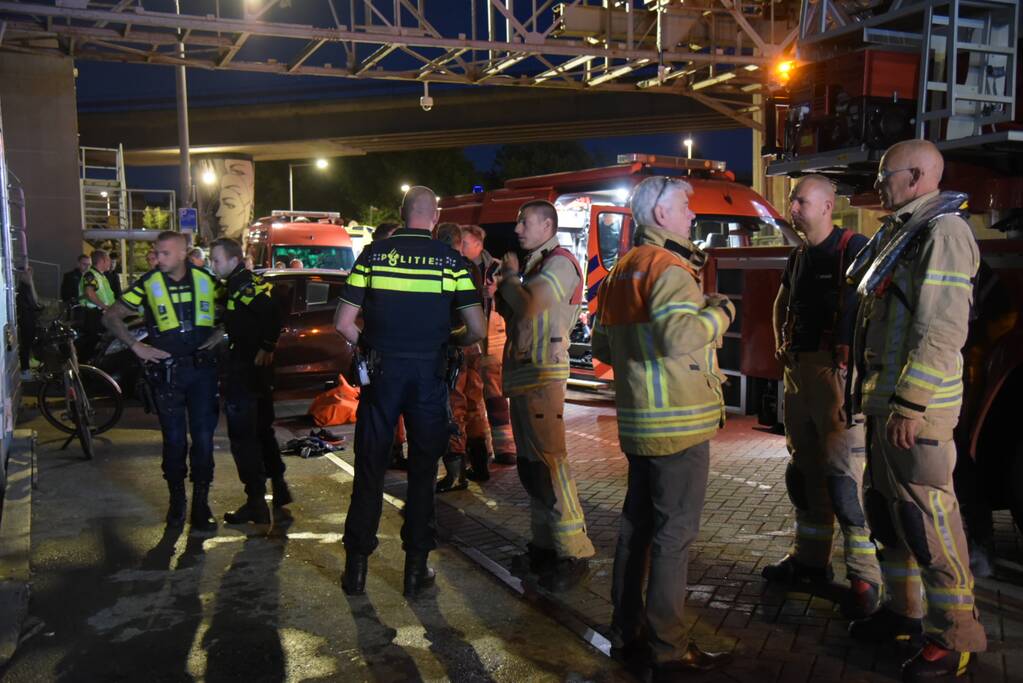 Omstanders halen persoon uit te water geraakte auto