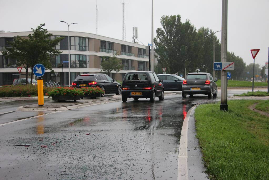 Boodschappenbus klapt achterop auto voor rotonde