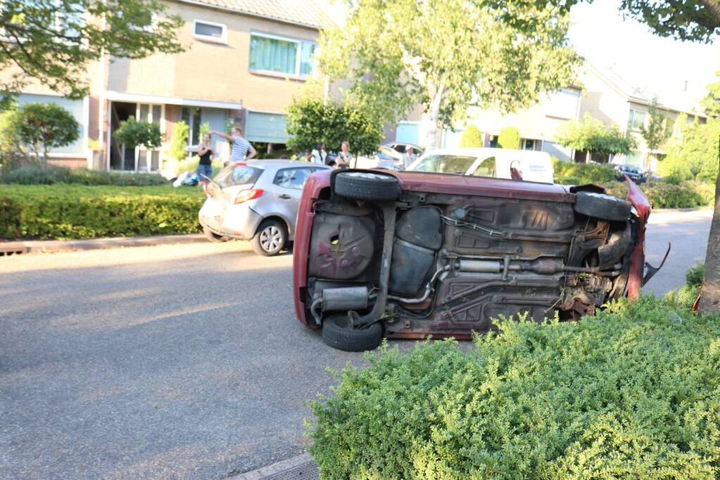 Bestuurder raakt onwel, botst op geparkeerde auto en belandt op zijn kant
