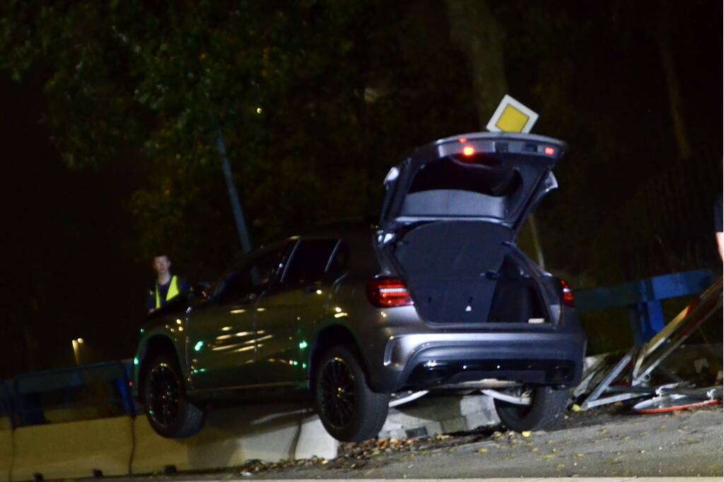 Auto belandt bovenop betonnen afscheiding