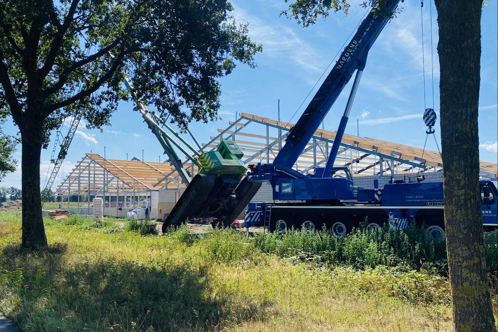 Bouwkraan achter stal omgevallen