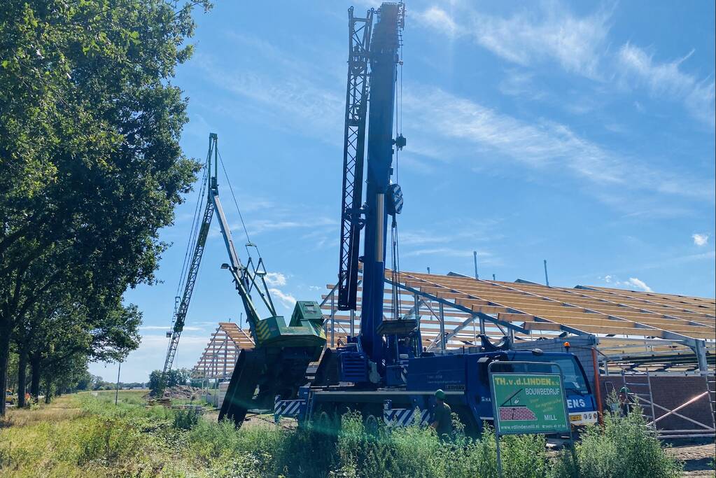 Bouwkraan achter stal omgevallen
