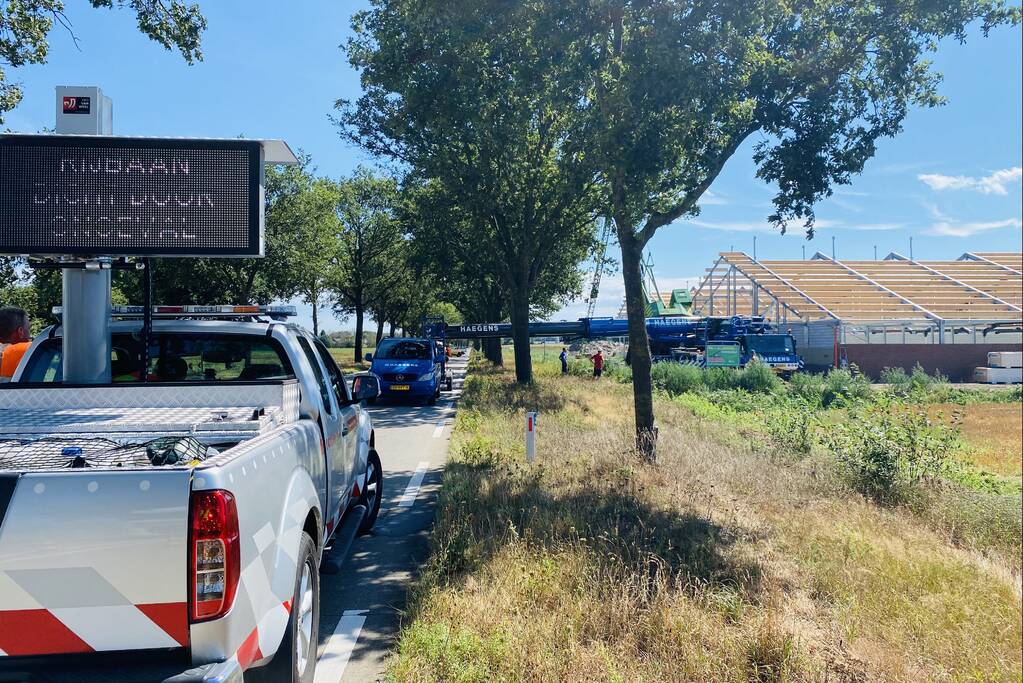 Bouwkraan achter stal omgevallen