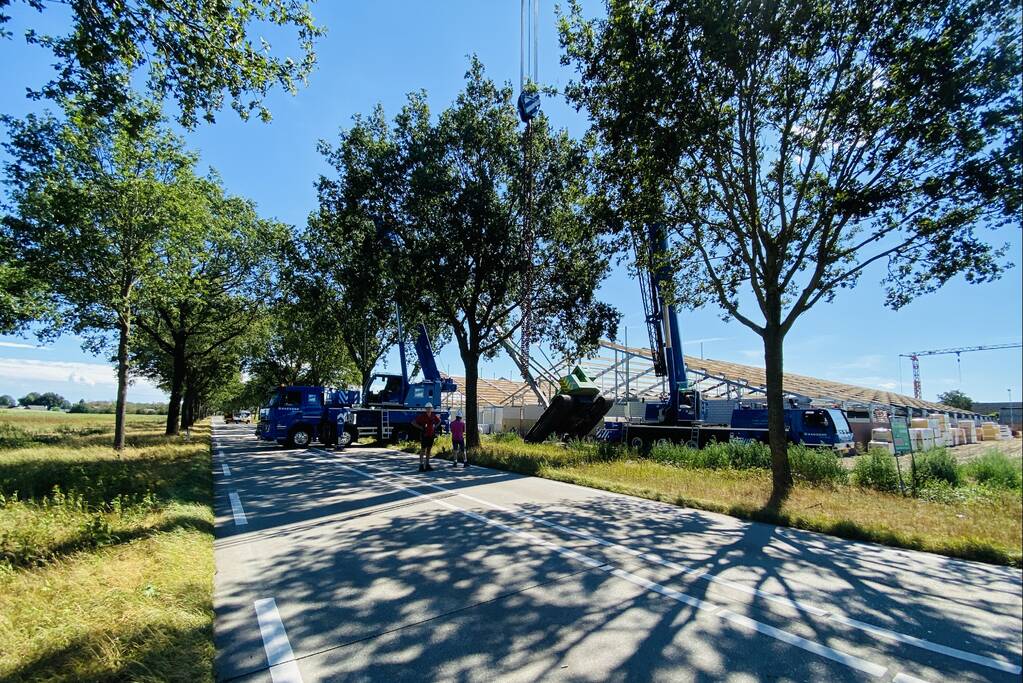 Bouwkraan achter stal omgevallen