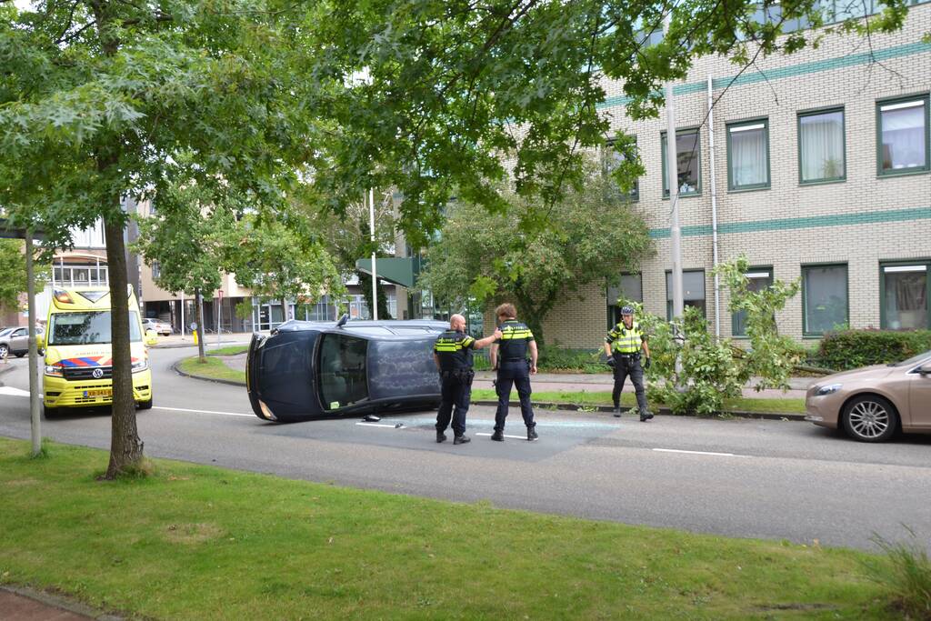 Auto vliegt uit de bocht en belandt op zijn kant
