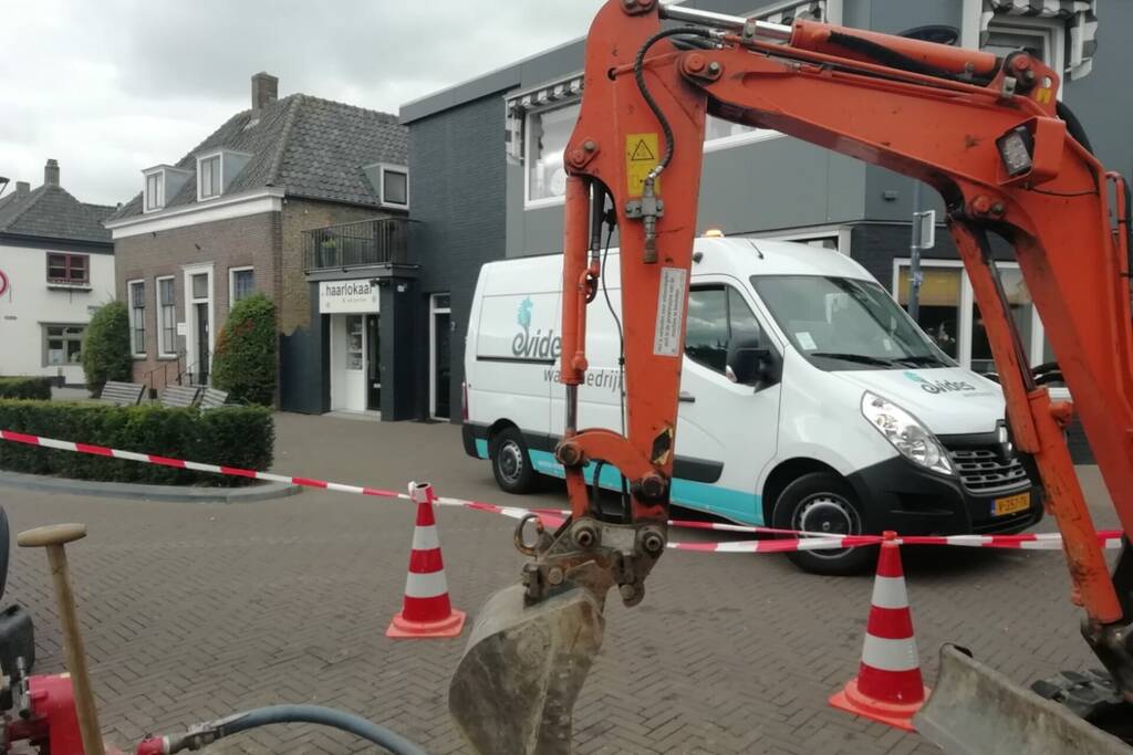 Straat opengebroken door gesprongen waterleiding
