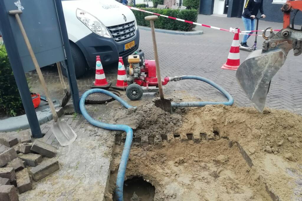 Straat opengebroken door gesprongen waterleiding