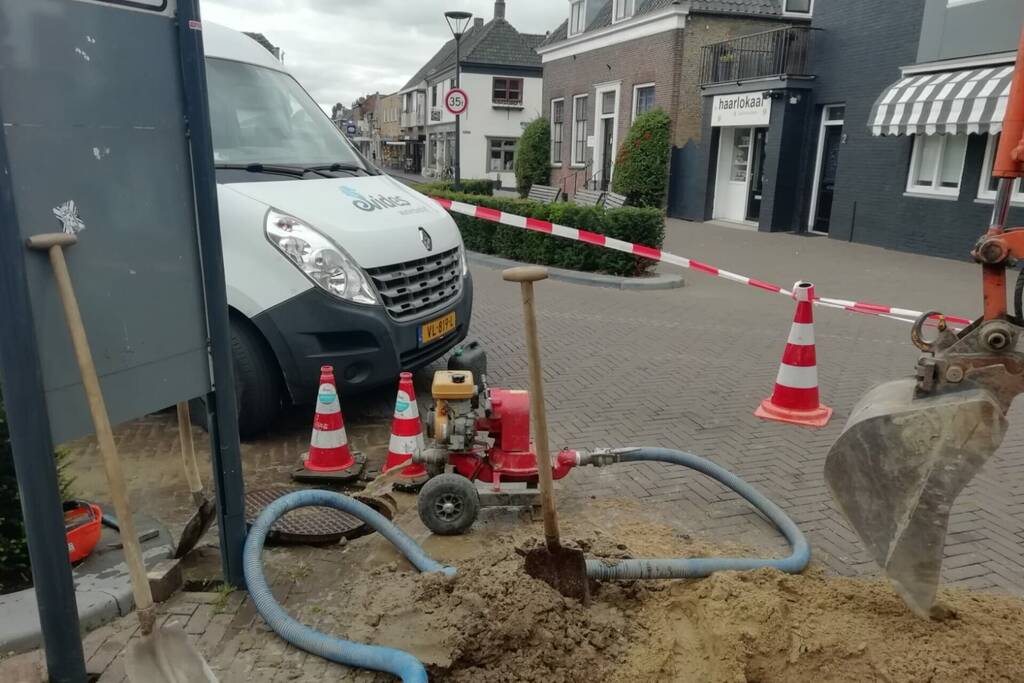 Straat opengebroken door gesprongen waterleiding