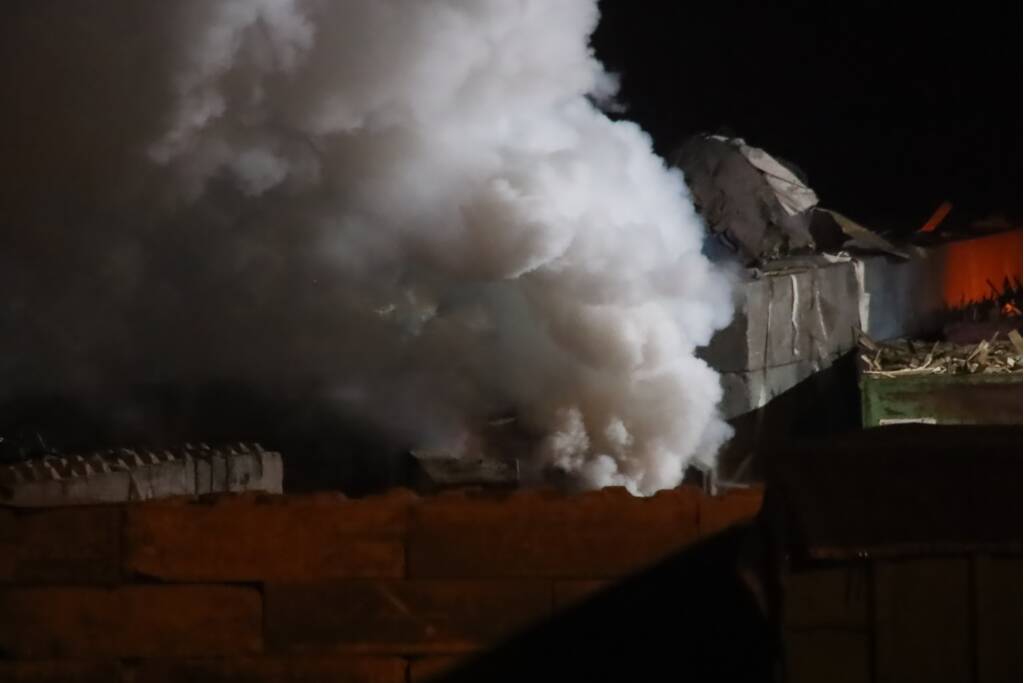 Grote berg afvalhout in brand naast houtopslag