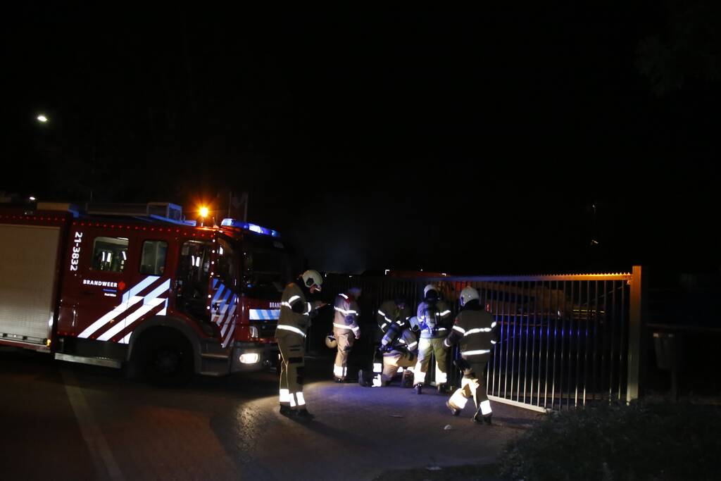 Grote berg afvalhout in brand naast houtopslag