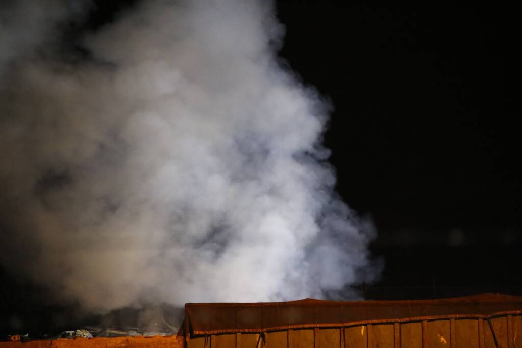 Grote berg afvalhout in brand naast houtopslag