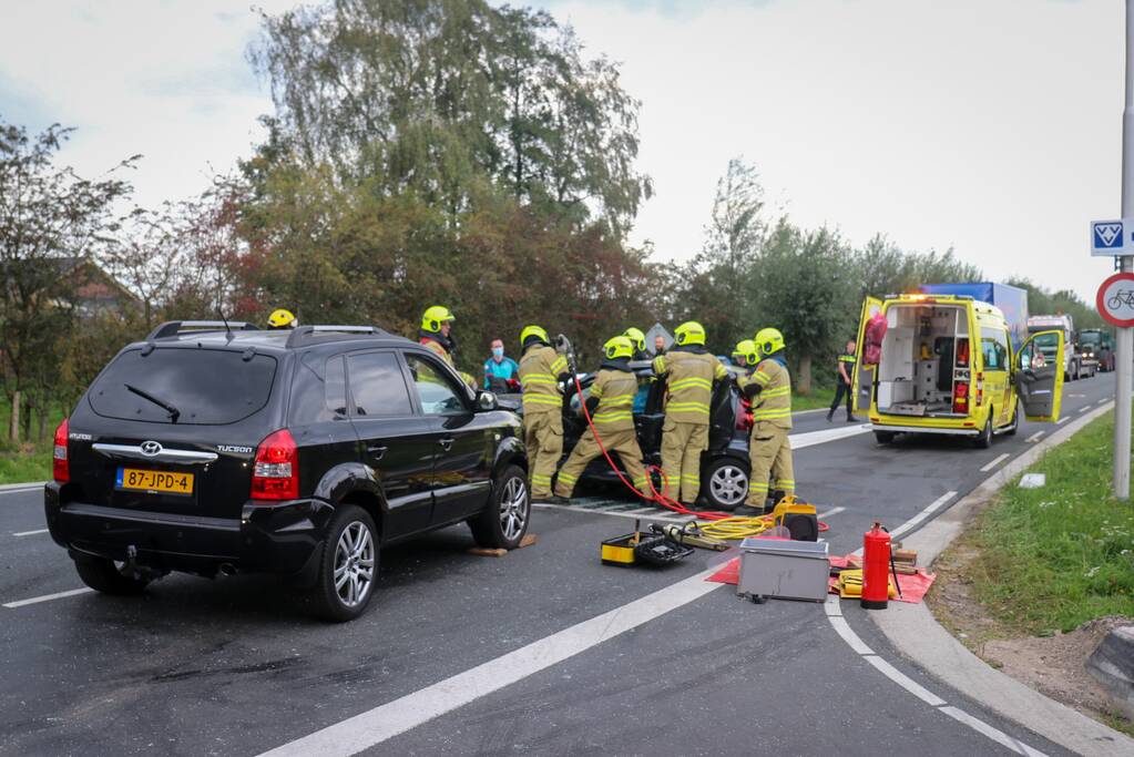Vrouw bekneld in voertuig bij aanrijding op kruising