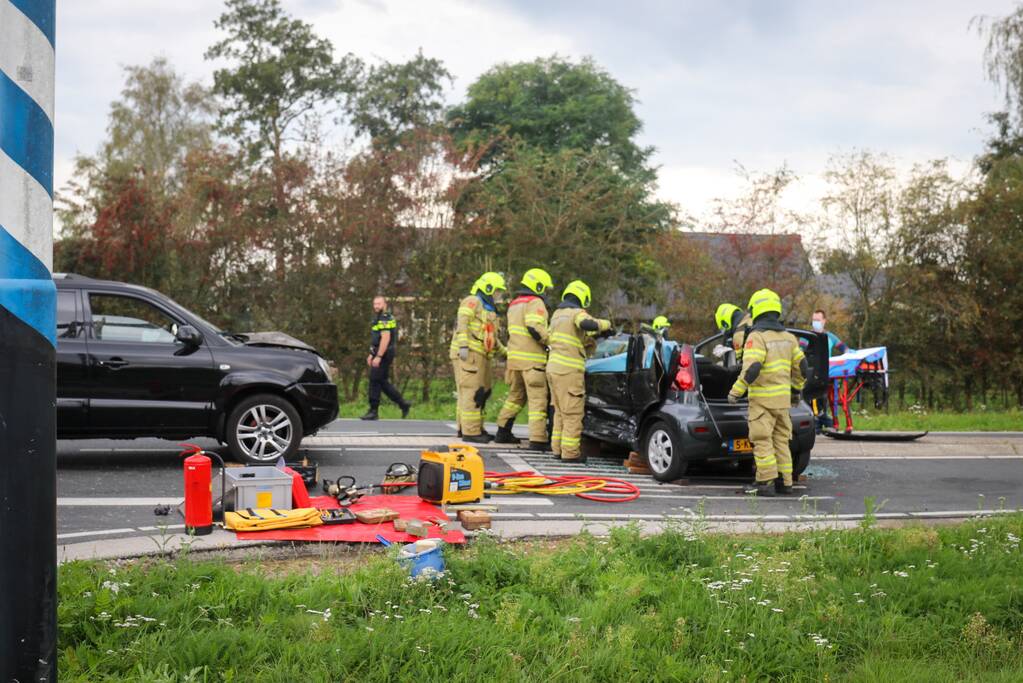 Vrouw bekneld in voertuig bij aanrijding op kruising