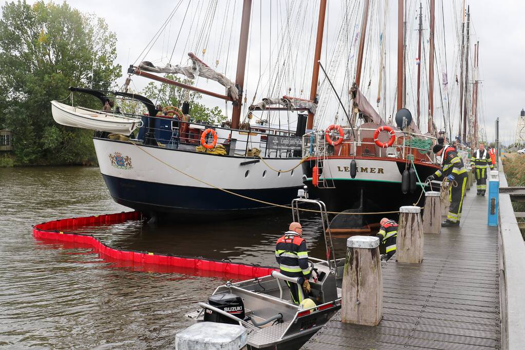 Brandweer plaats olieschermen voor lekkend zeilschip