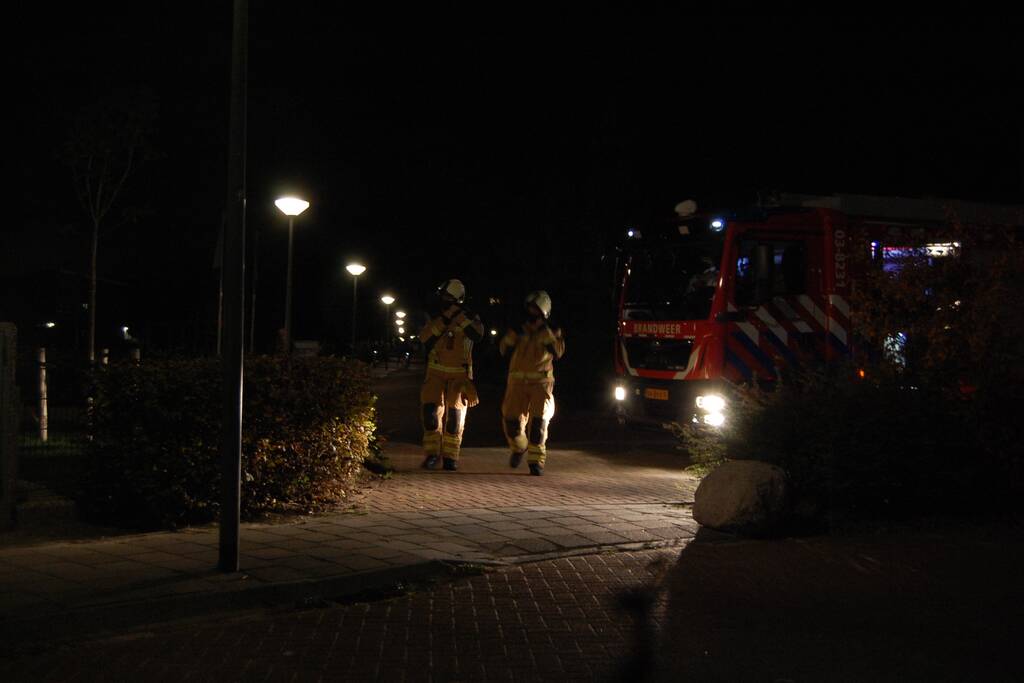 Brandweer blust brandende papiercontainer