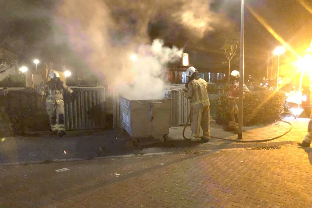 Brandweer blust brandende papiercontainer