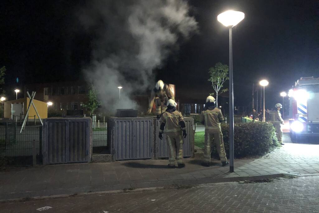 Brandweer blust brandende papiercontainer