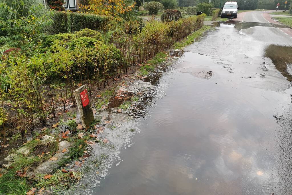 Straat onder water door gesprongen waterleiding