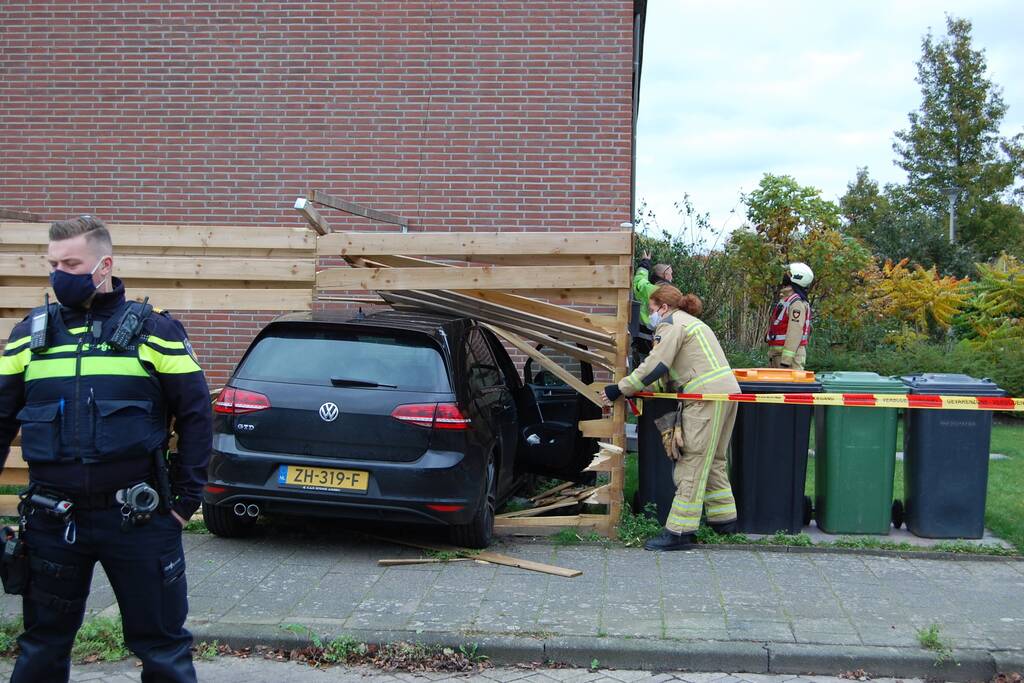 Personenauto rijdt door schutting
