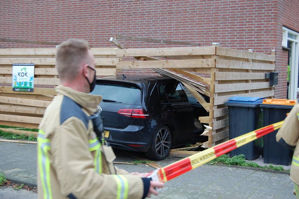 Personenauto rijdt door schutting