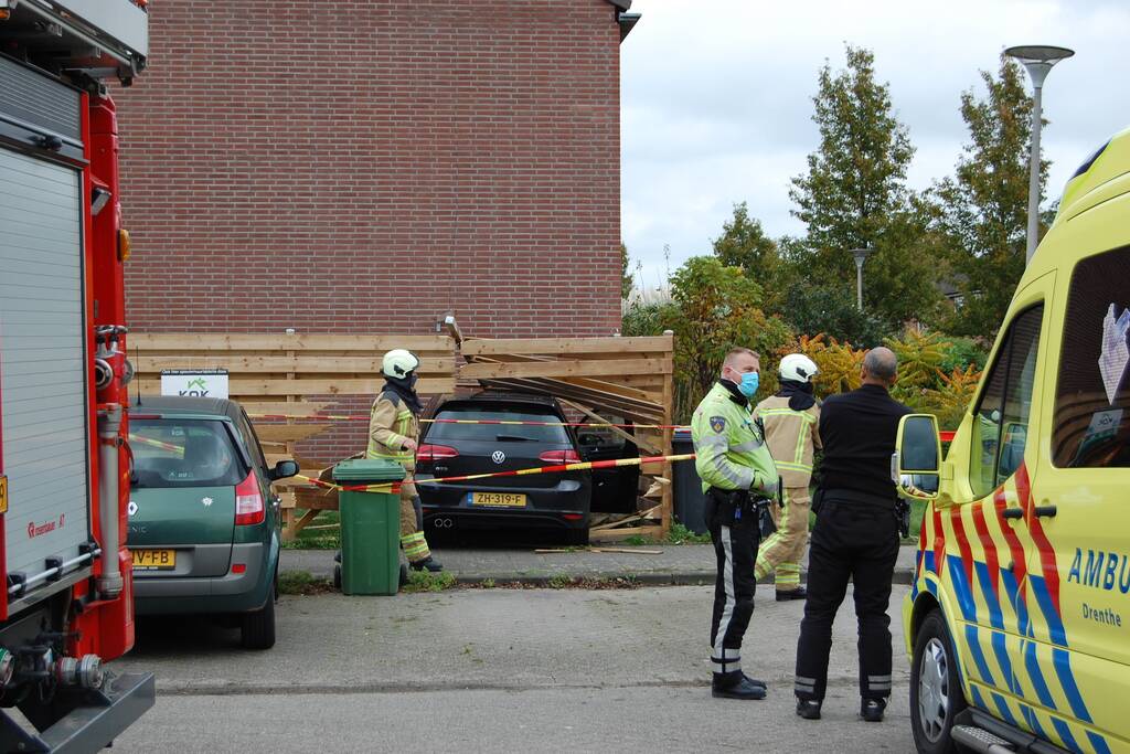 Personenauto rijdt door schutting