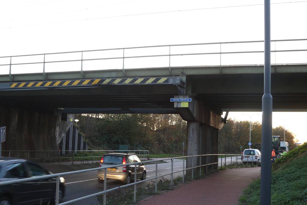 Vrachtwagen met graafmachine ramt spoorbrug