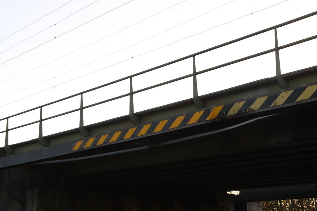 Vrachtwagen met graafmachine ramt spoorbrug