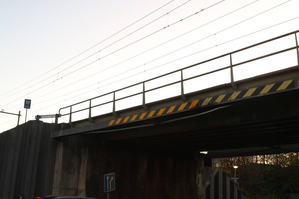 Vrachtwagen met graafmachine ramt spoorbrug