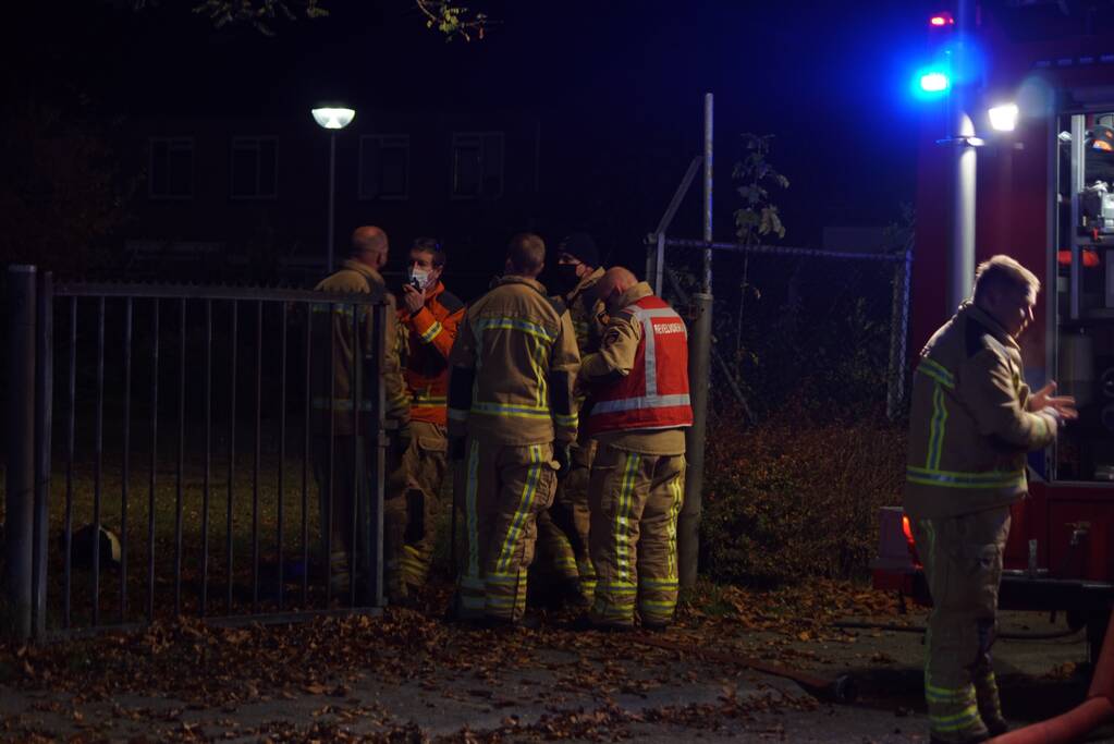 Berg afval in brand achter schoolgebouw