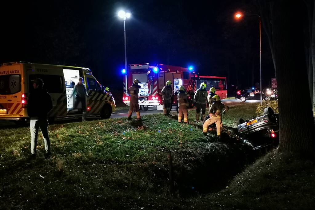 Personenauto ligt op zijn kop in berm