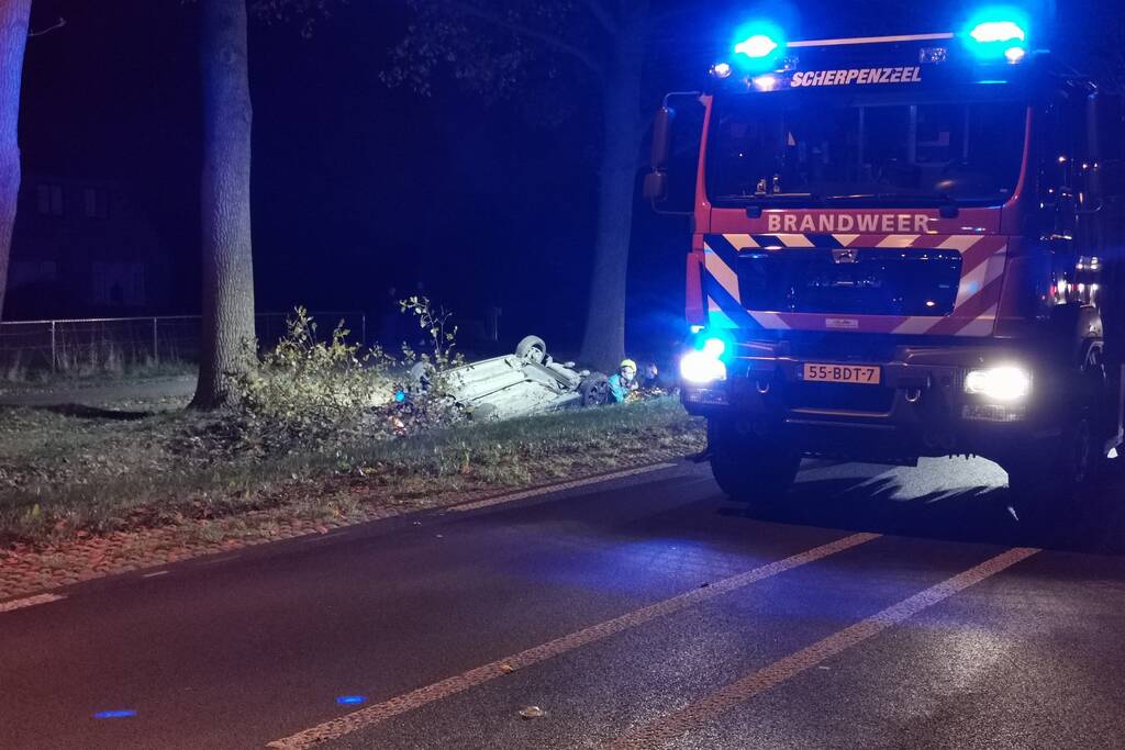 Personenauto ligt op zijn kop in berm