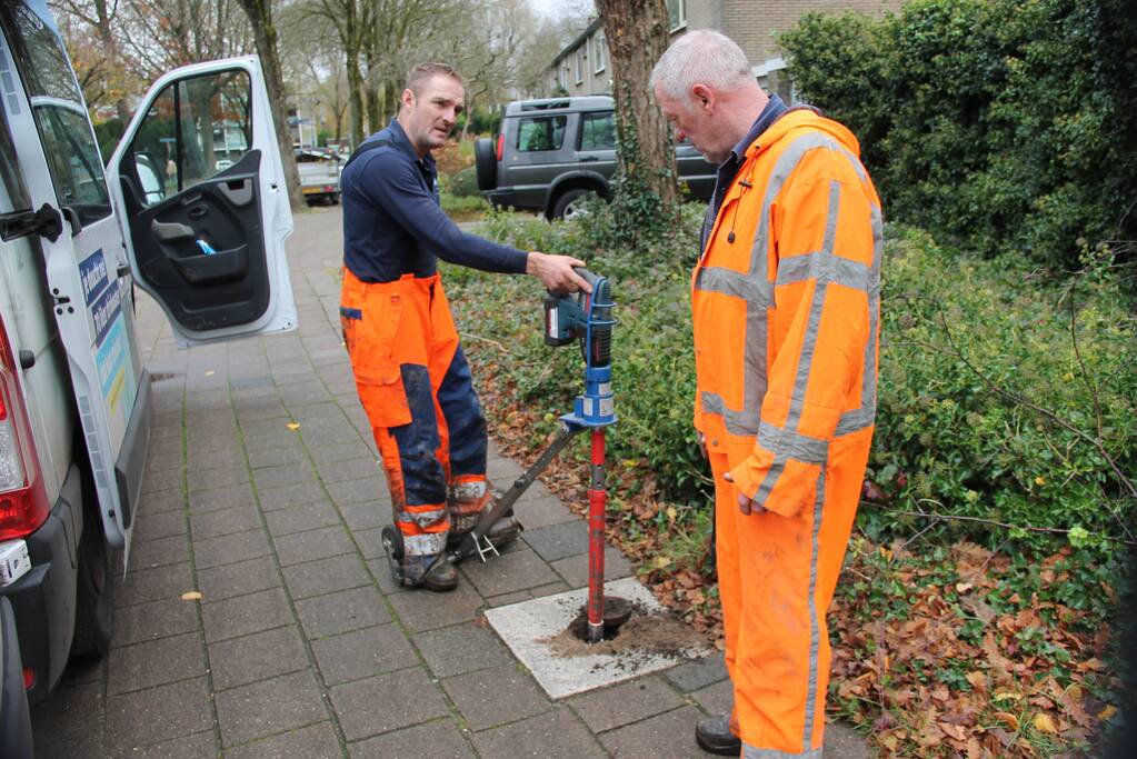 Straat opengebroken door gesprongen waterleiding in Smitsveen