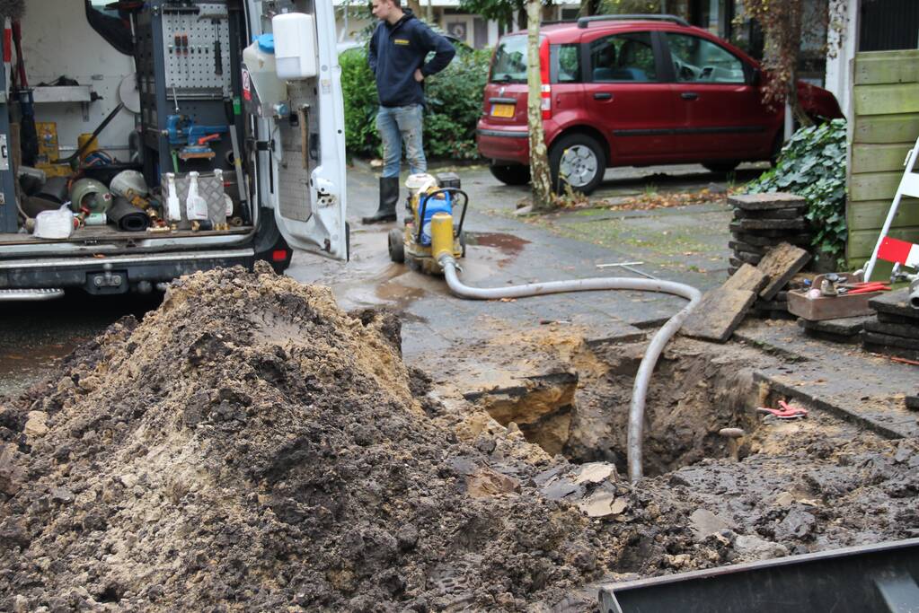 Straat opengebroken door gesprongen waterleiding in Smitsveen