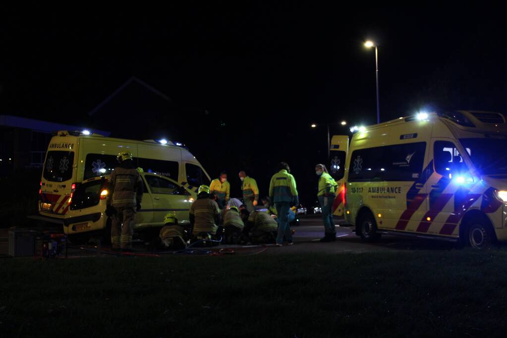 Fietser bekneld onder auto