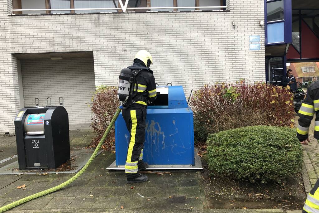 Omstanders blussen brand in papiercontainer