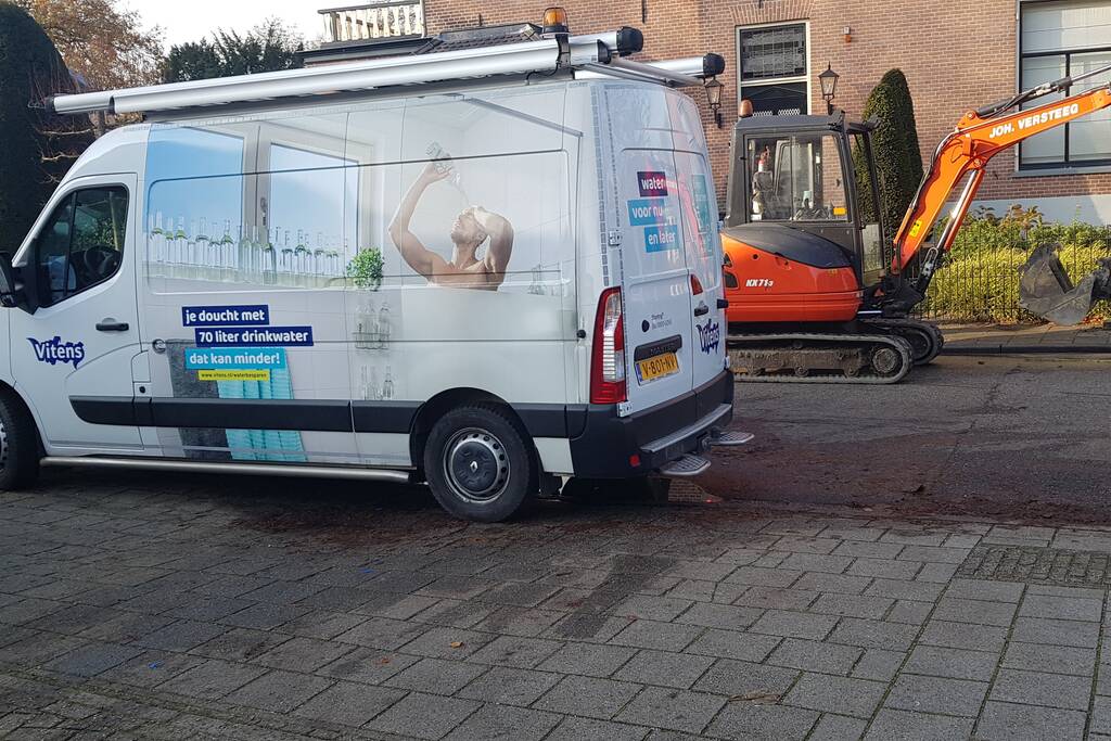 Straat opengebroken door gesprongen waterleiding