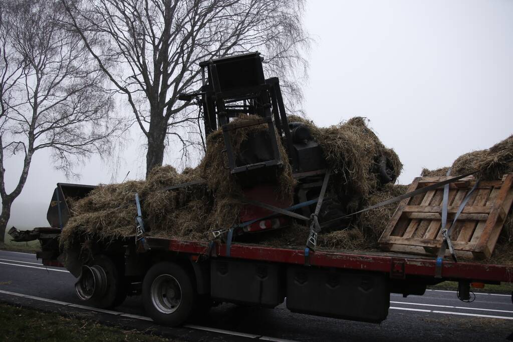 Vrachtwagen met aanhanger met hooi ramt boom