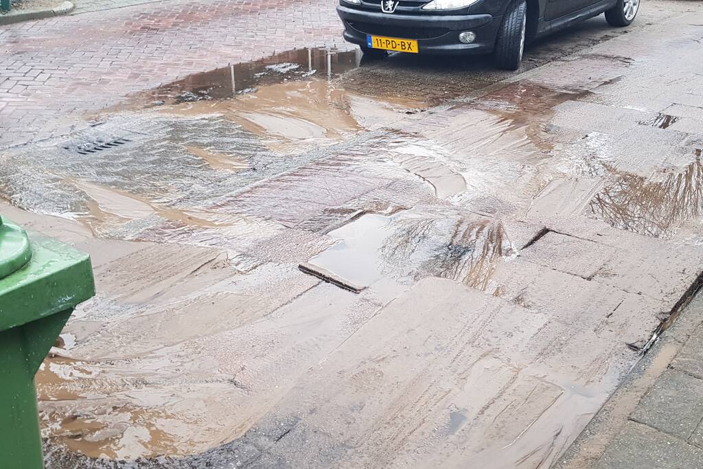 Leidingbreuk zorgt voor zand en water over de weg