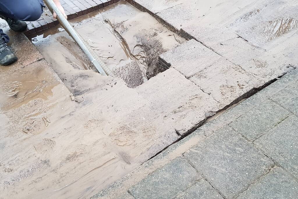 Leidingbreuk zorgt voor zand en water over de weg