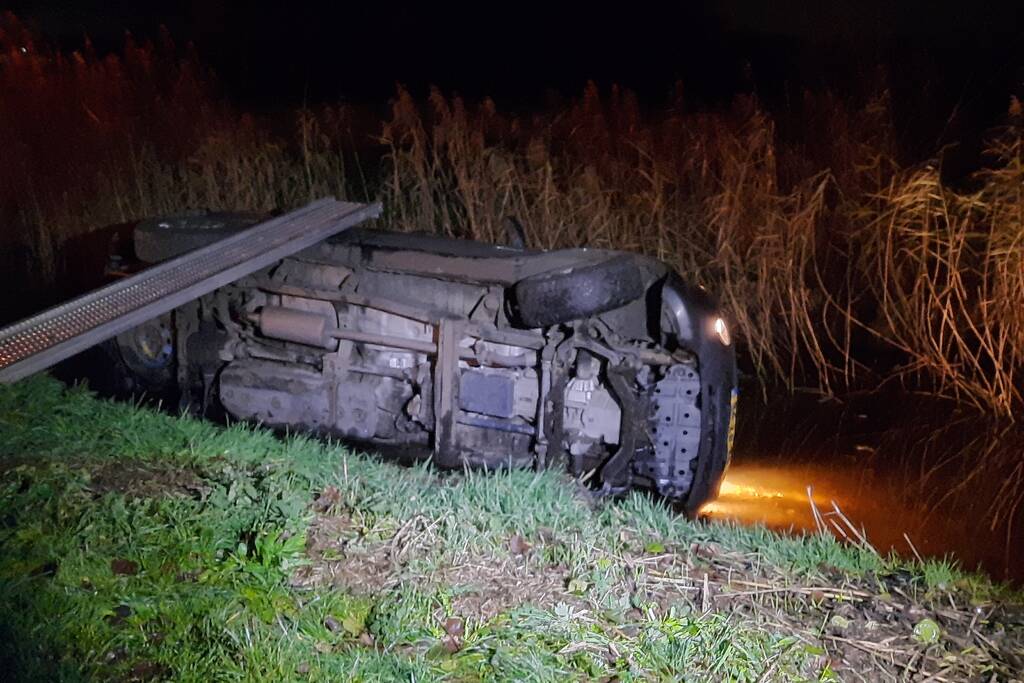 Auto vliegt uit de bocht en belandt op zijn kant in sloot