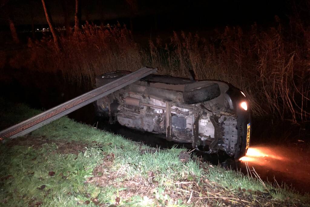 Auto vliegt uit de bocht en belandt op zijn kant in sloot