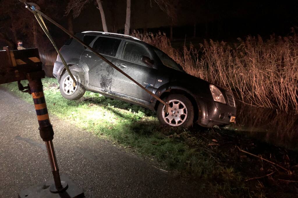 Auto vliegt uit de bocht en belandt op zijn kant in sloot