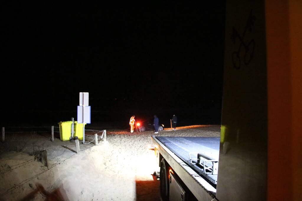 Automobilist rijdt auto vast op strand