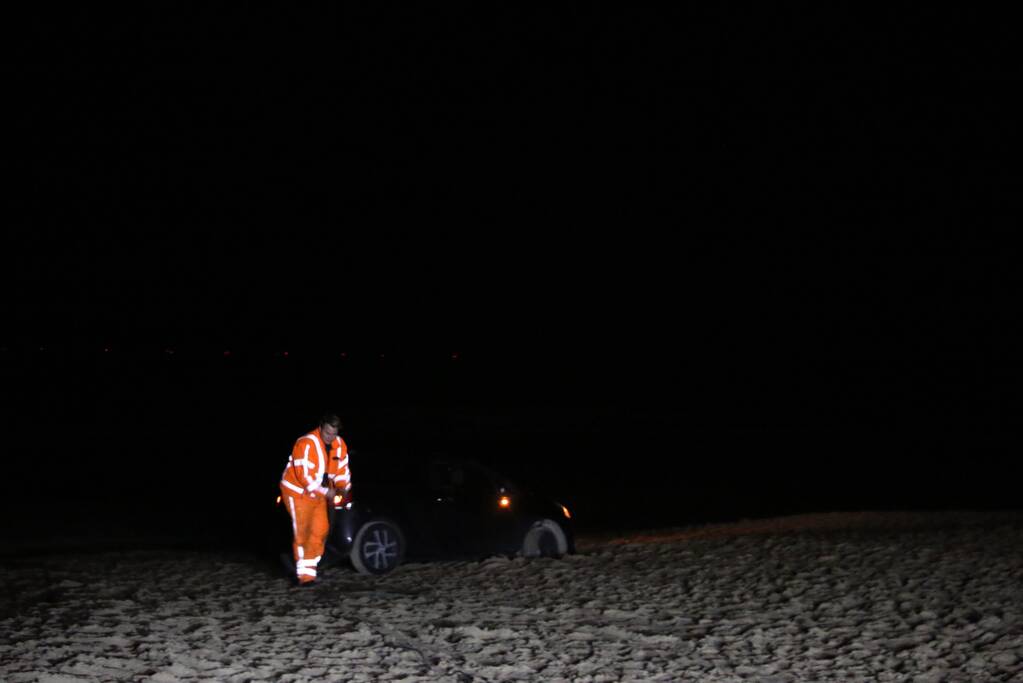 Automobilist rijdt auto vast op strand