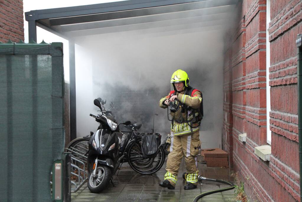 Brand onder overkapping van woning